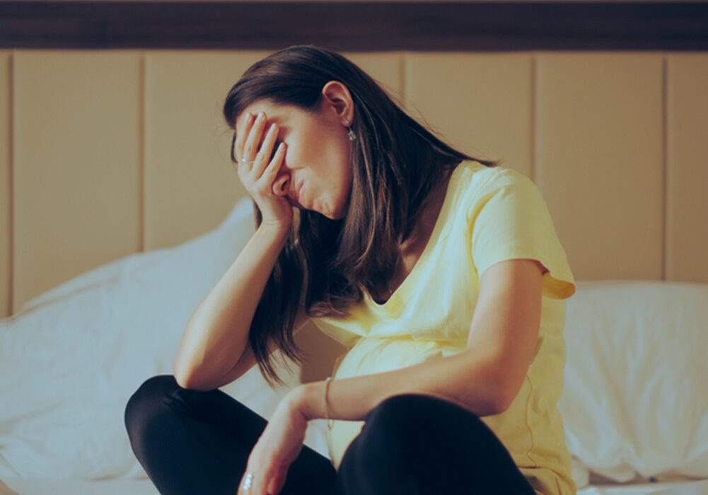 A woman sitting in distress with her hand over her face.