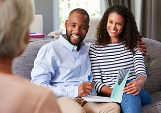 Happy young couple taking financial advice at home.